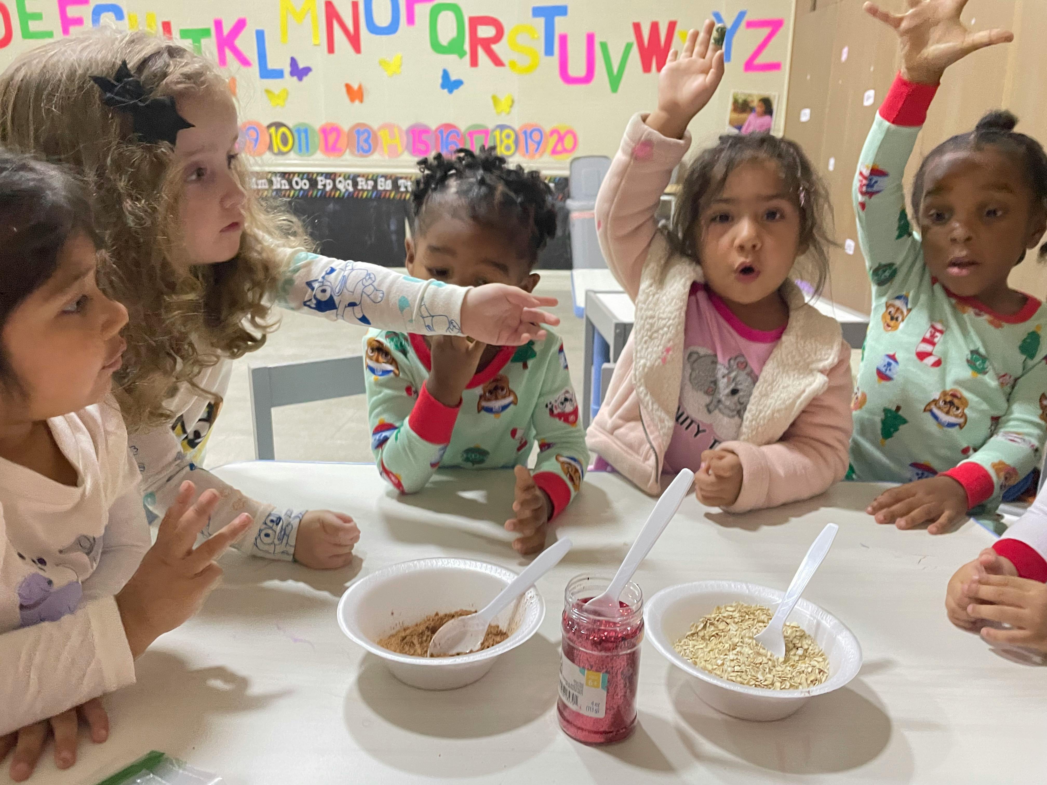 Children at a table with bowls, some raising their hands