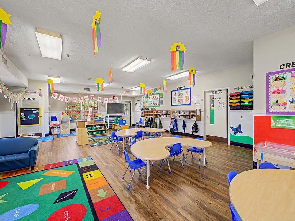Empty colorful preschool classroom with small tables and chairs