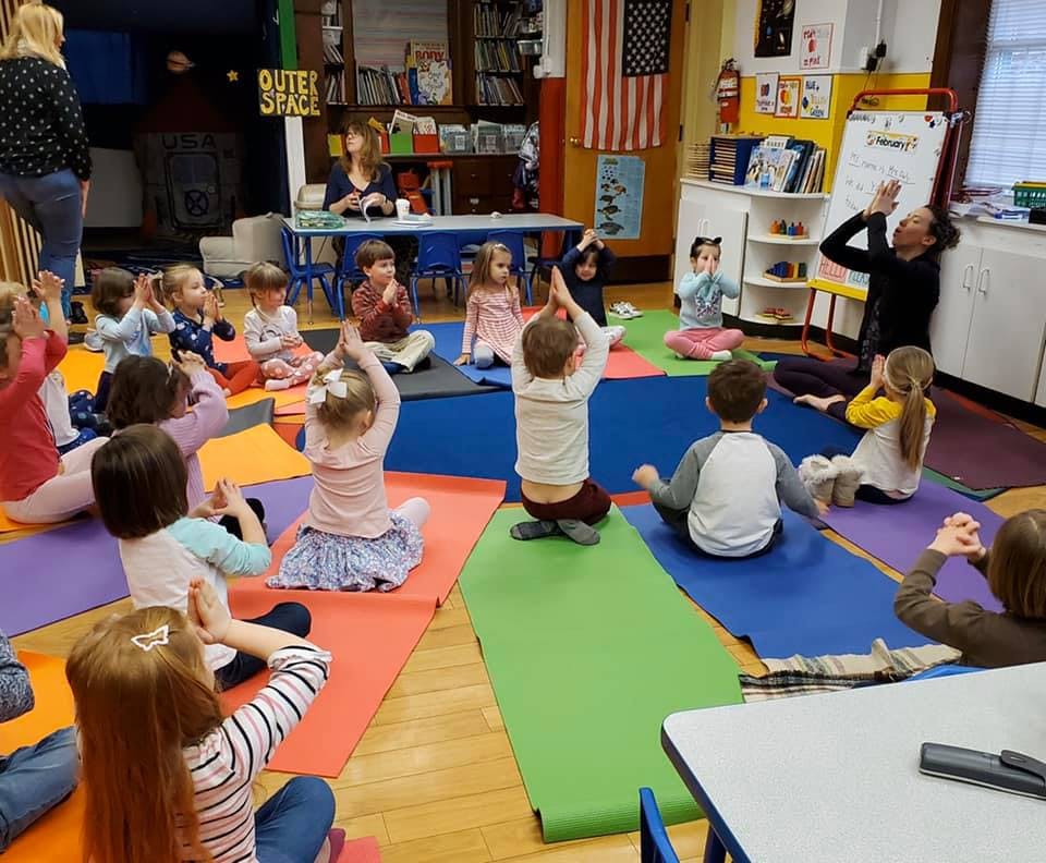 Adult leading a group of children in a yoga class