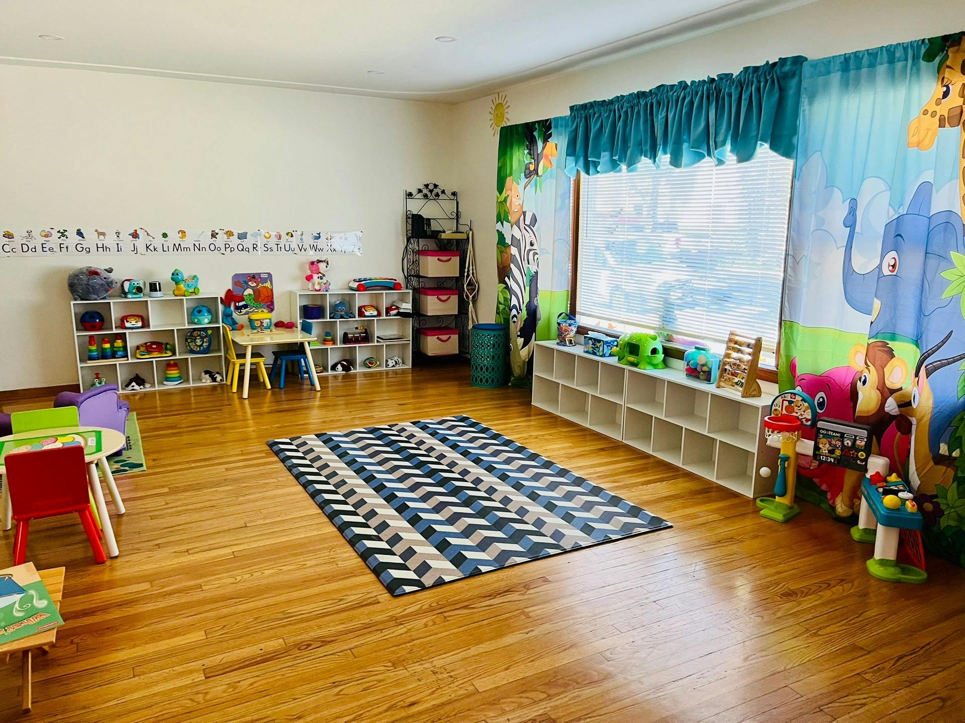 Playroom with small tables and chairs, shelves with toys, and a patterned rug