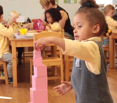 Child stacking pink blocks in a classroom