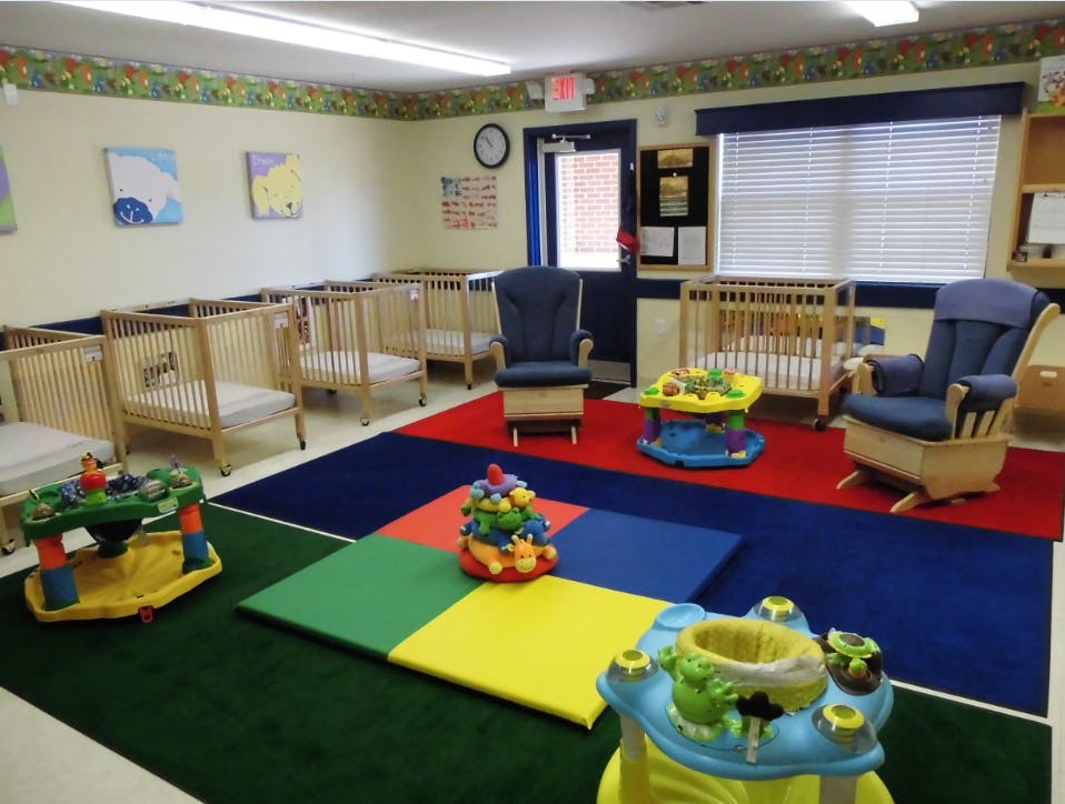 Daycare room with cribs, play mats, and infant toys