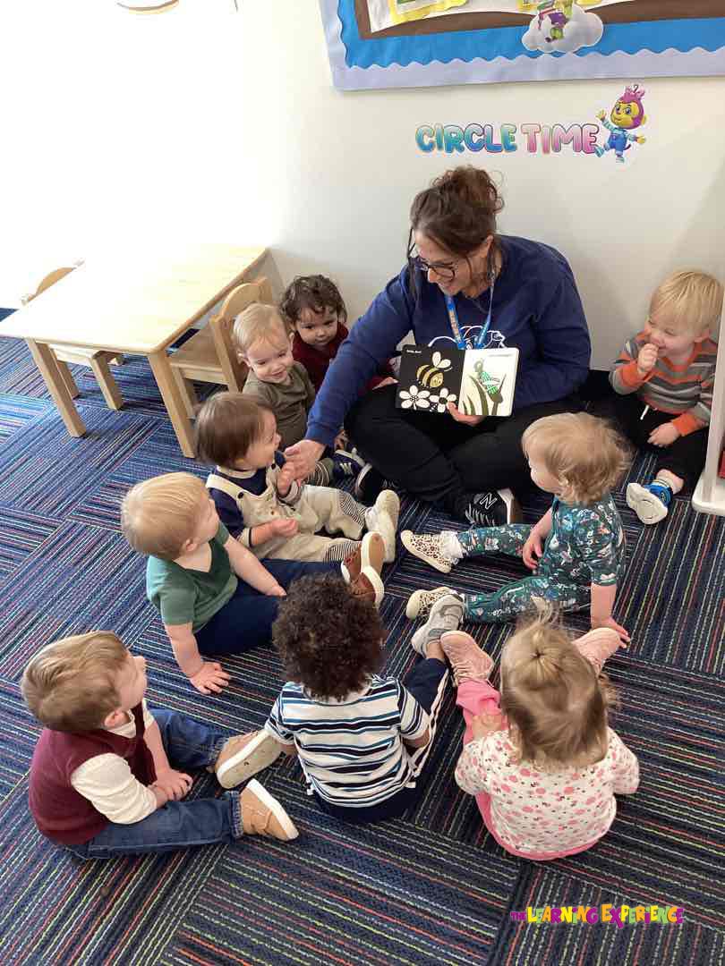 Adult and multiple children sitting on a floor during circle time