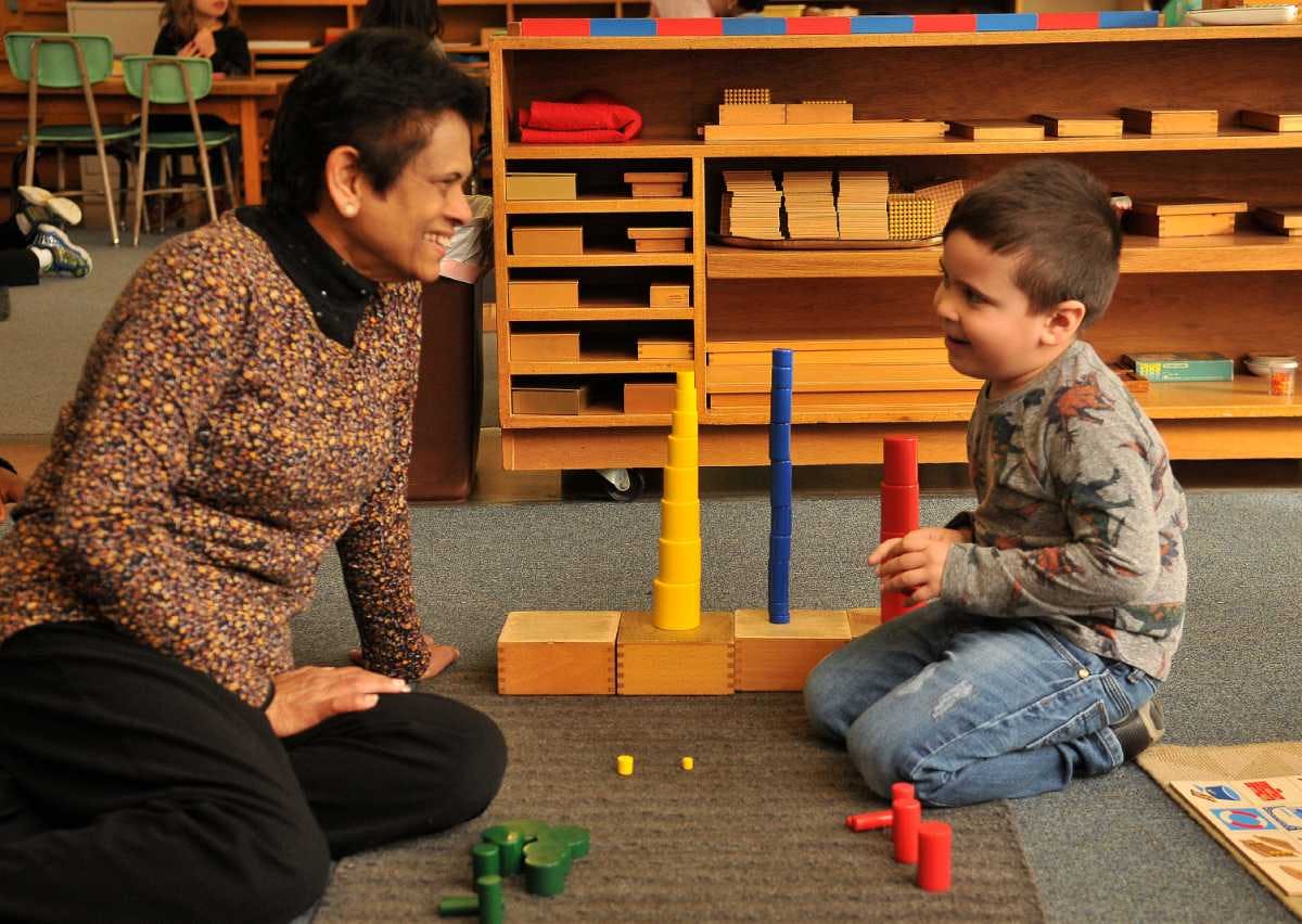 Adult and child kneeling on floor playing with colorful stacking toys