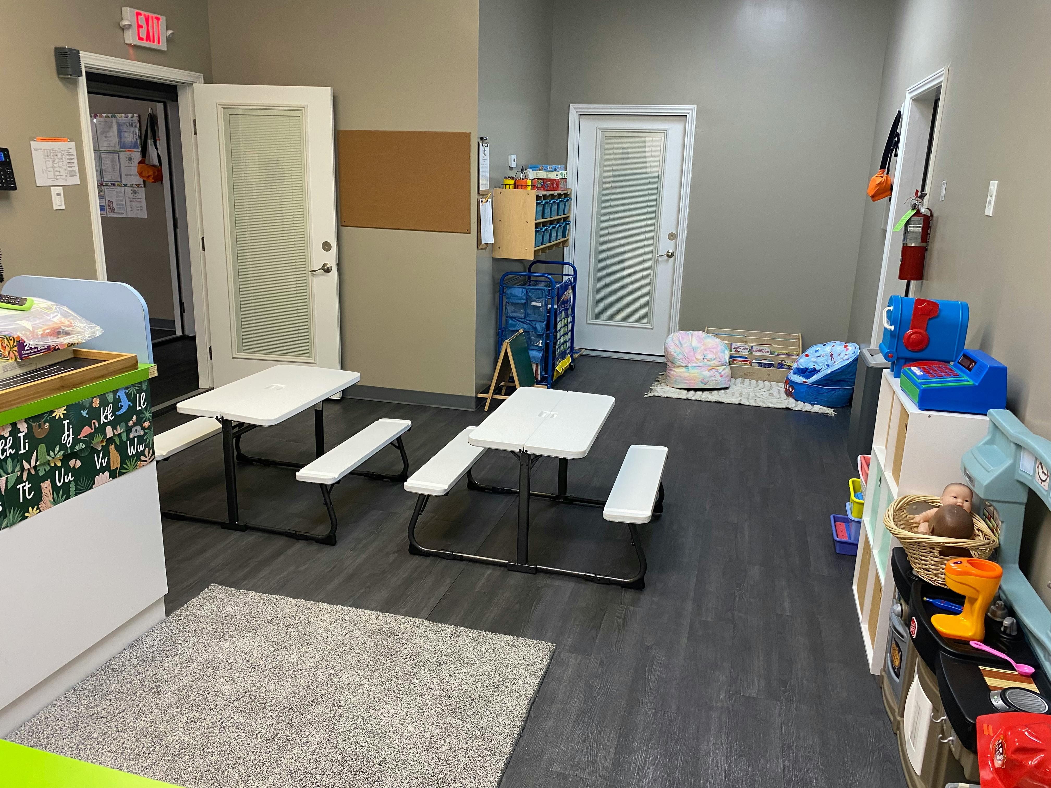 Two small white picnic tables with benches in a room