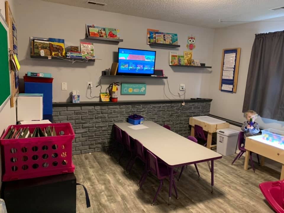Classroom with long table, chairs, television, and shelves with books