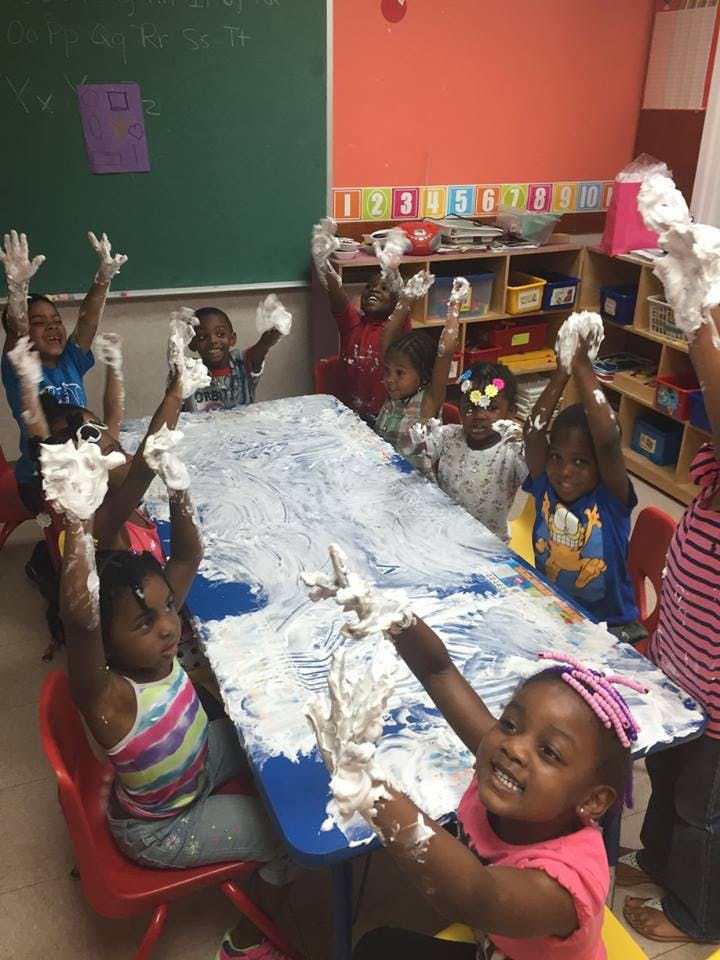 Children playing with shaving cream at a table in a classroom