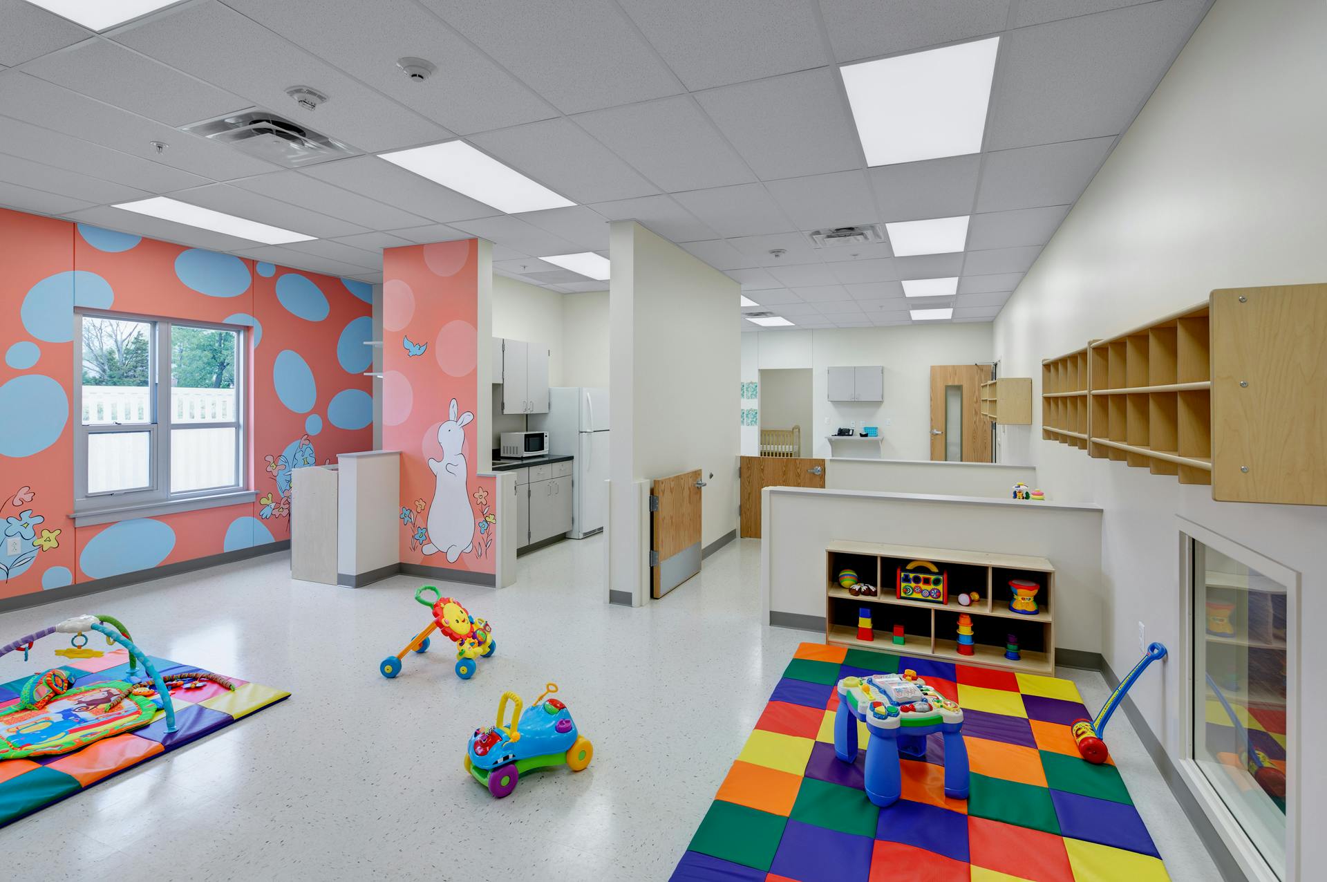Playroom with colorful rug, toys, and patterned walls