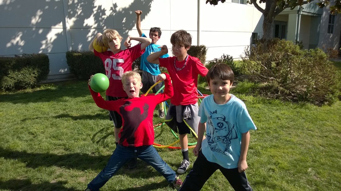 Children playing with a green ball and hoops outdoors