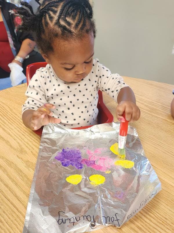 Child painting on foil with a brush