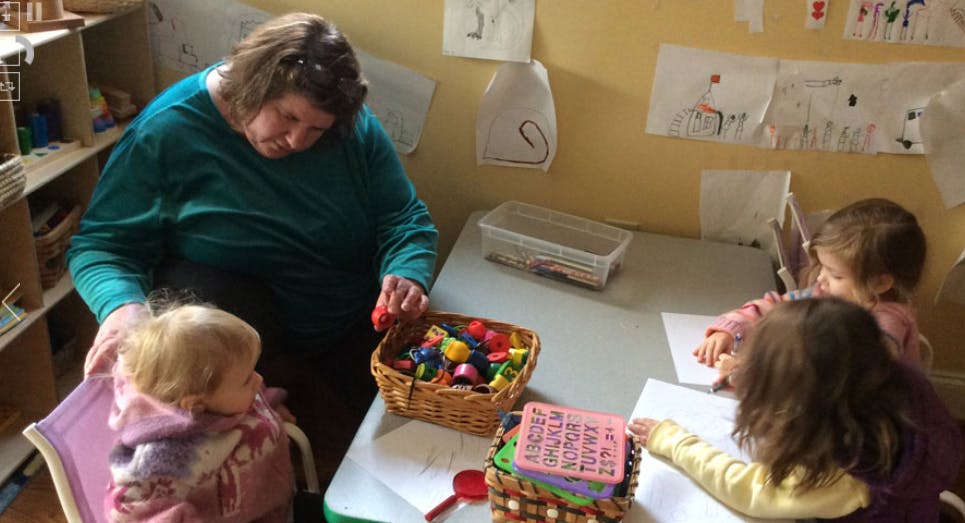 Adult and children at a table with a basket of colorful objects
