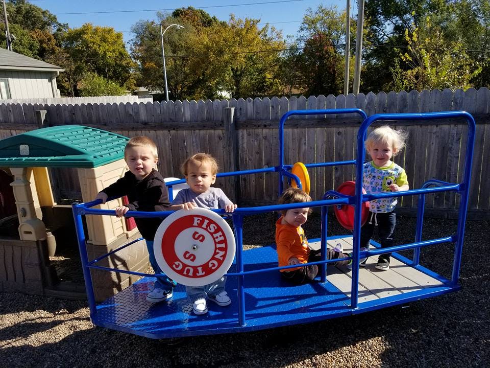 Four children playing on a blue boat-shaped playground structure
