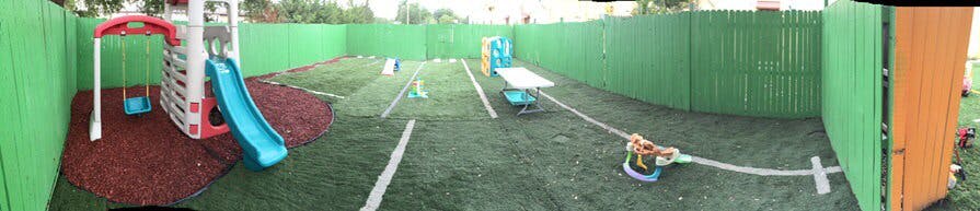 Outdoor playground with green fence, slide, and play equipment