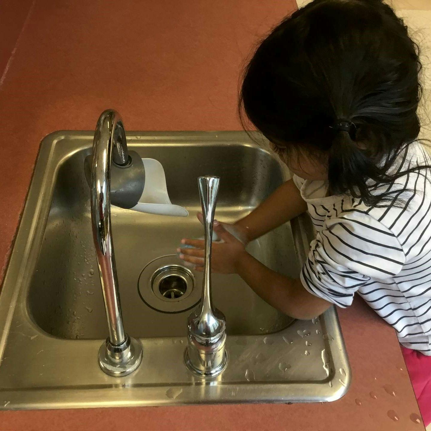 Child washing hands in a sink