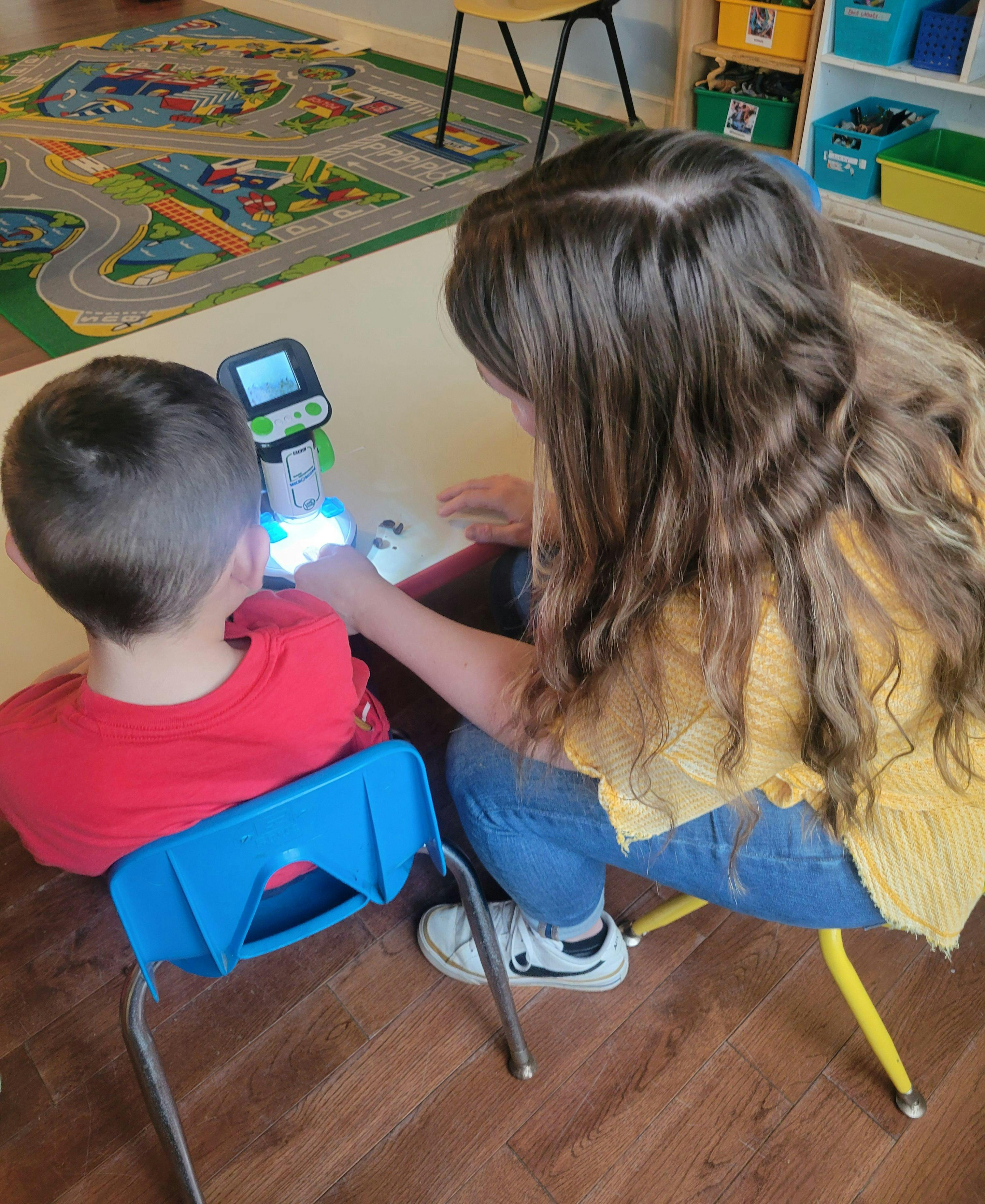 Child and person using a digital microscope on a table
