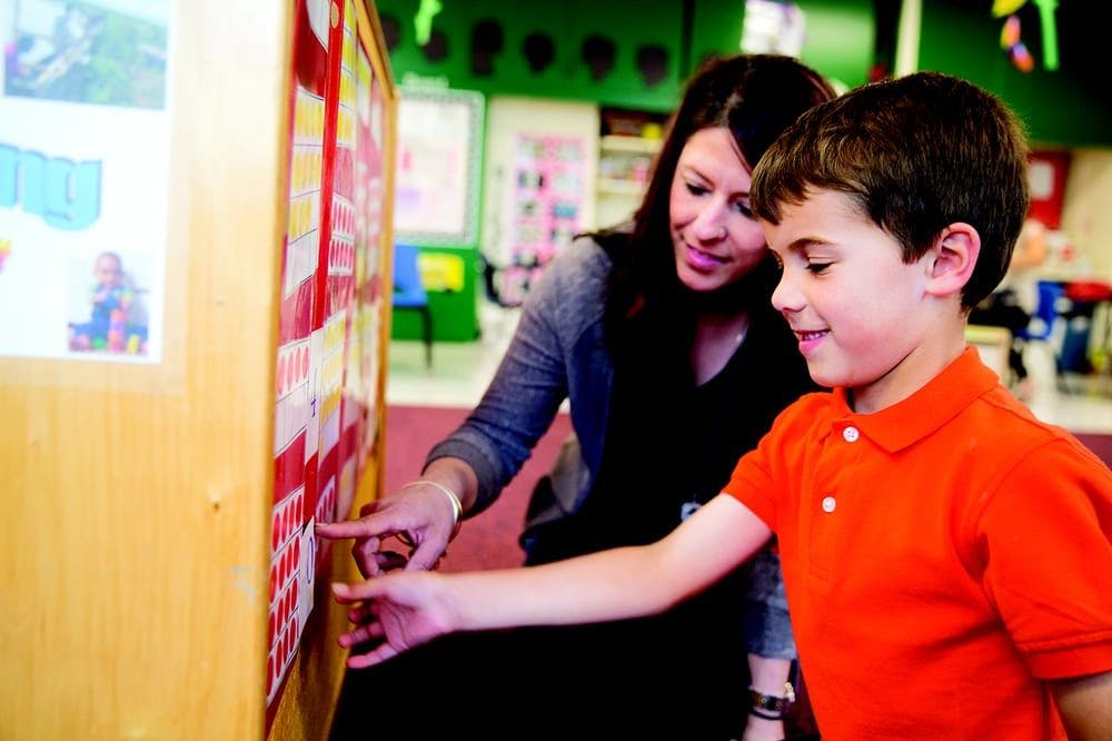 Adult and child pointing at a display board in a classroom