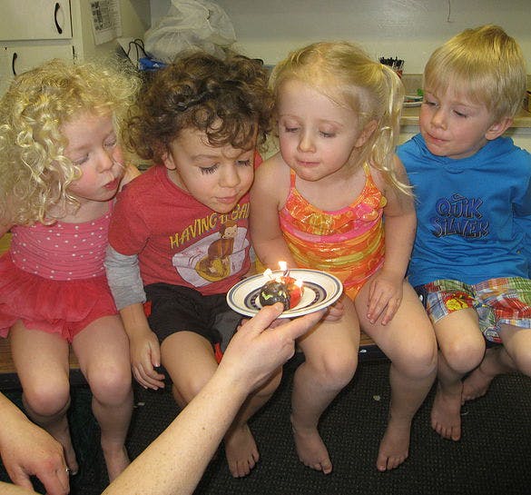 Children blowing out candles on a small cake