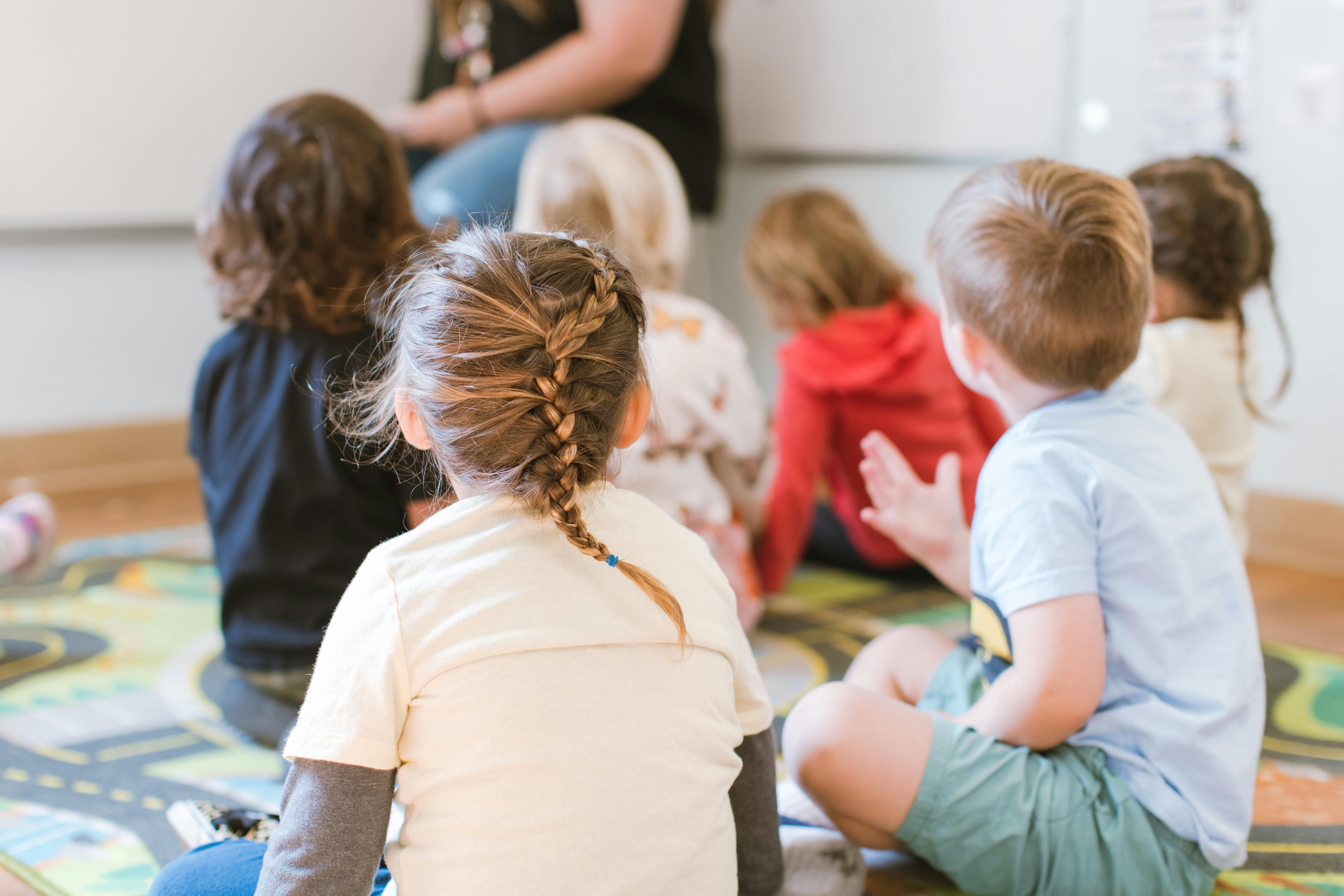 Children sitting on a rug in a classroom