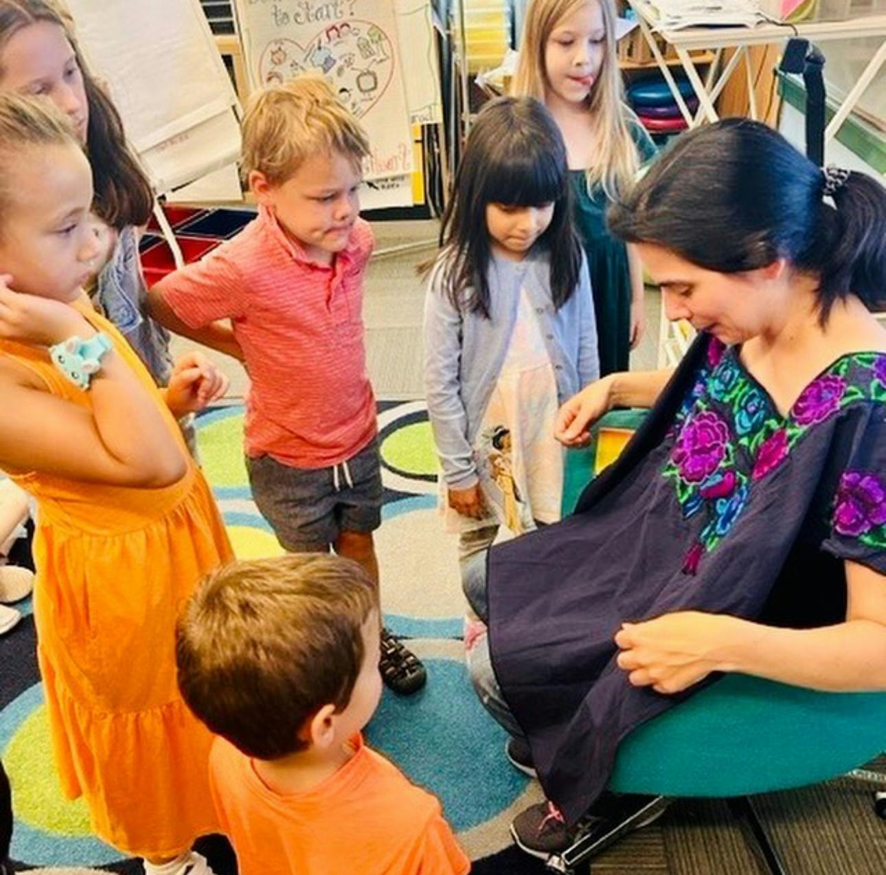 Adult showing clothing to children in a classroom