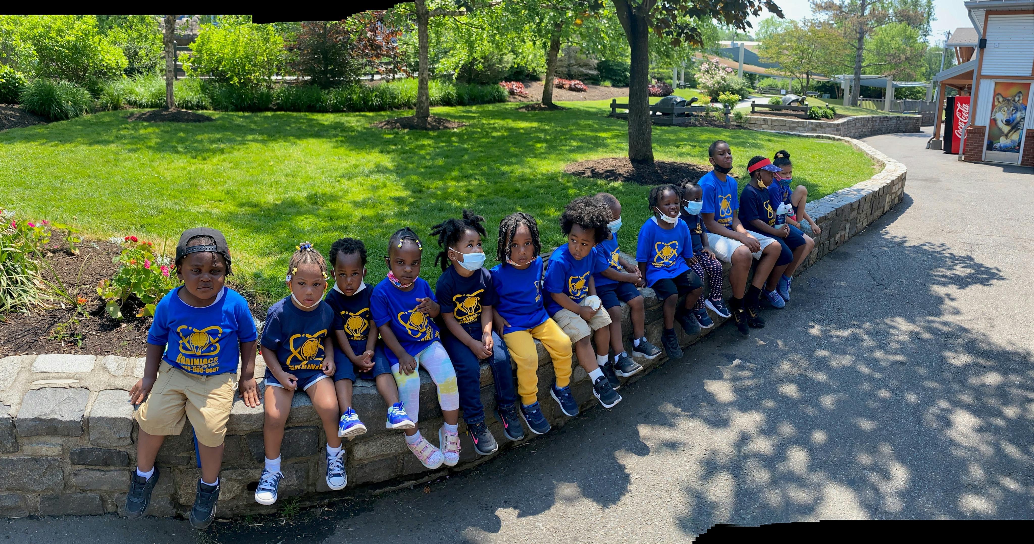 Group of children and adults sitting on a low stone wall outdoors