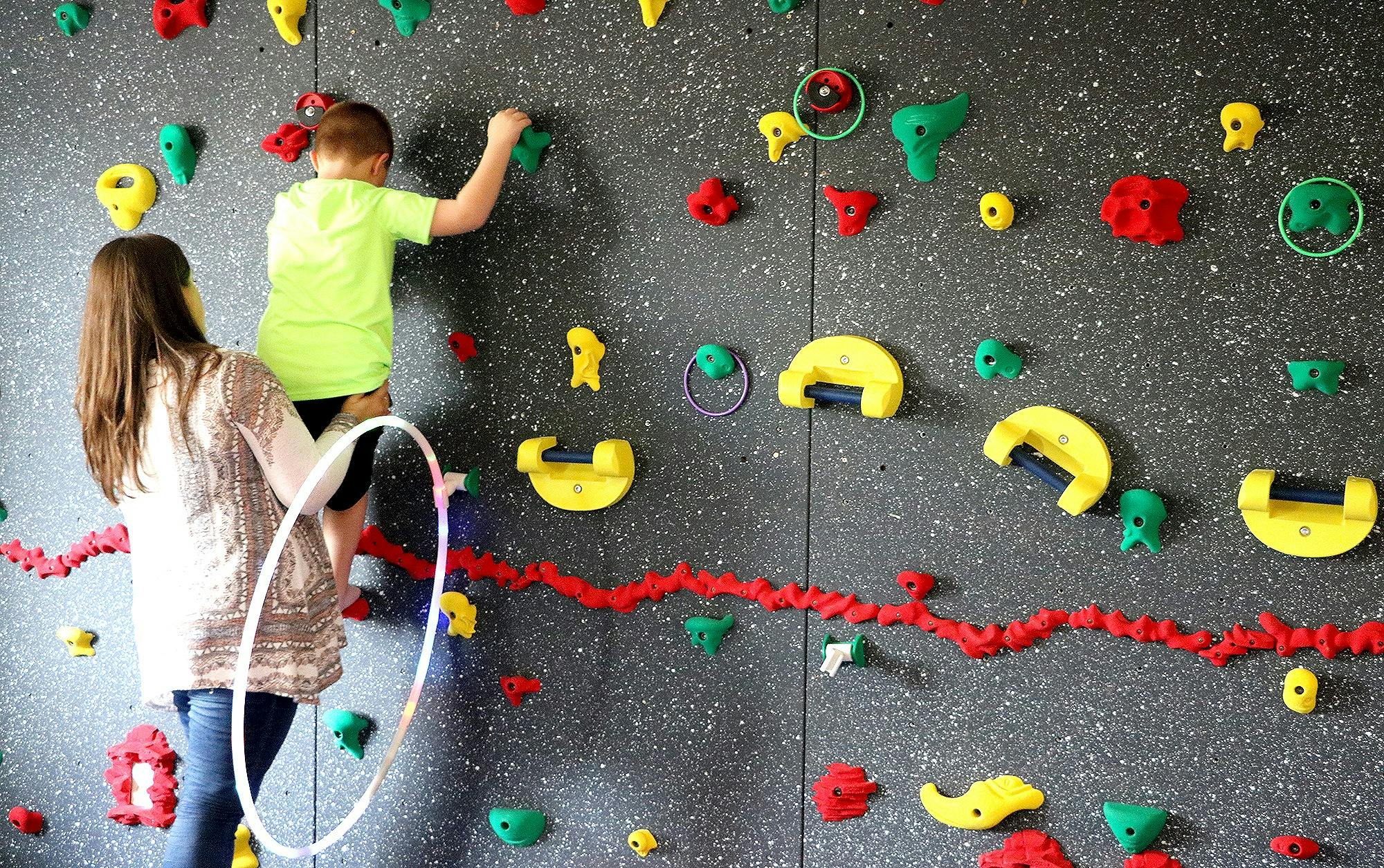 Person helping a child climb a rock wall