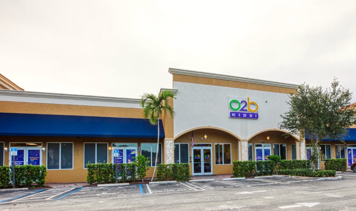 Exterior view of an O2b Kids! building with a blue awning