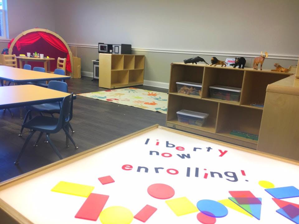 Classroom with tables, chairs, shelves, and a light table with shapes and text