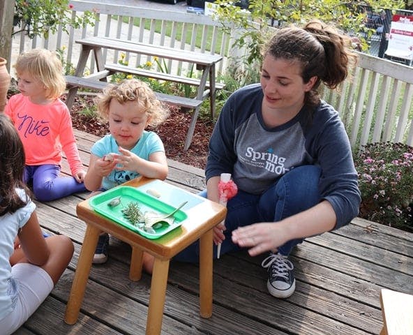Adult and children on a deck with a child playing at a small table