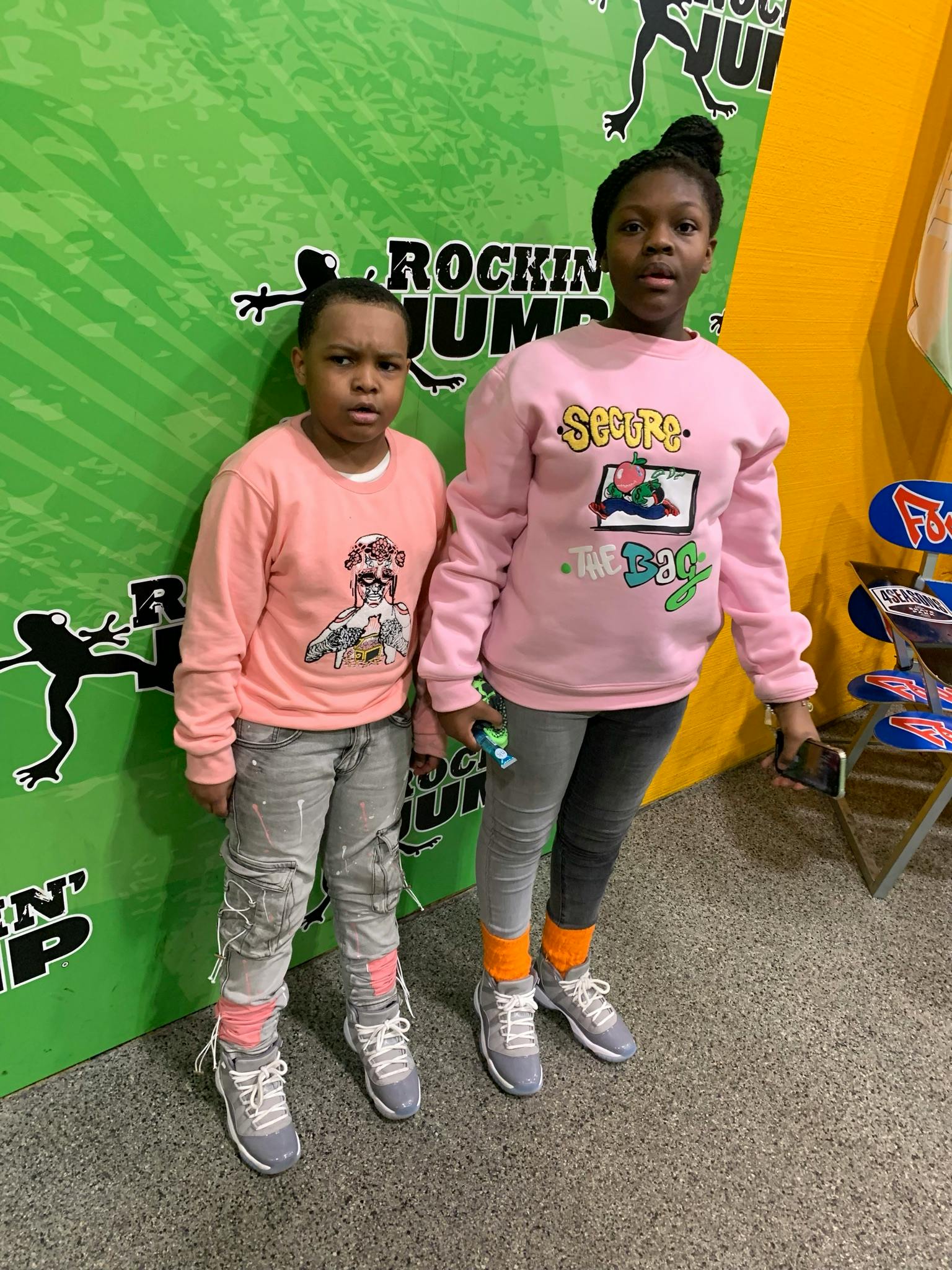 Two children standing in front of a green wall with text