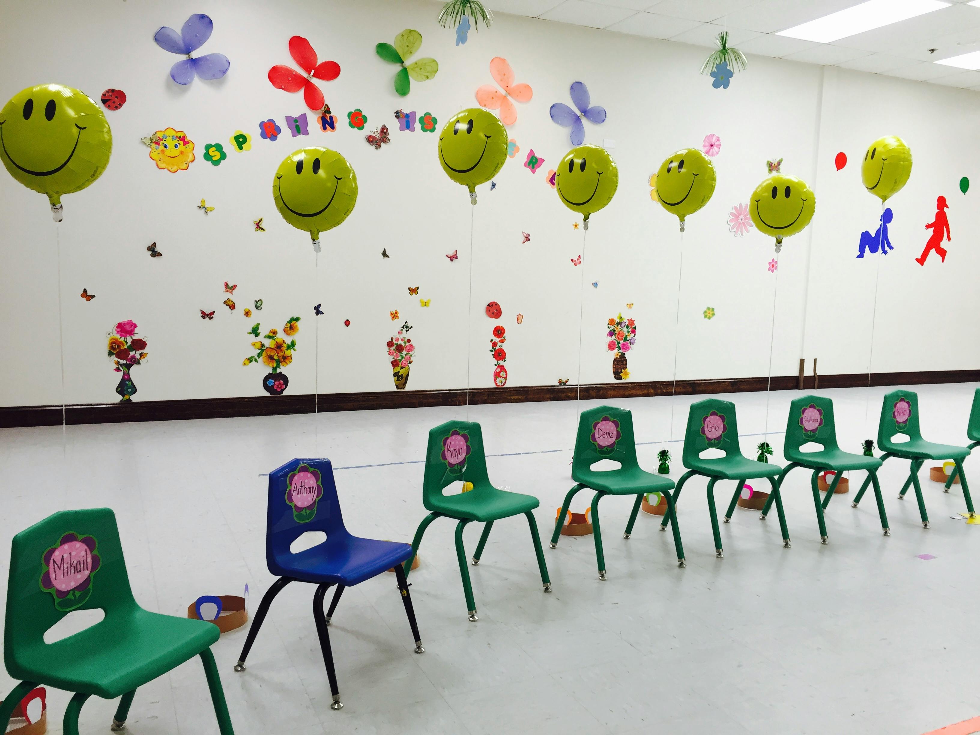 Classroom with green and blue chairs and smiley face balloons on the wall