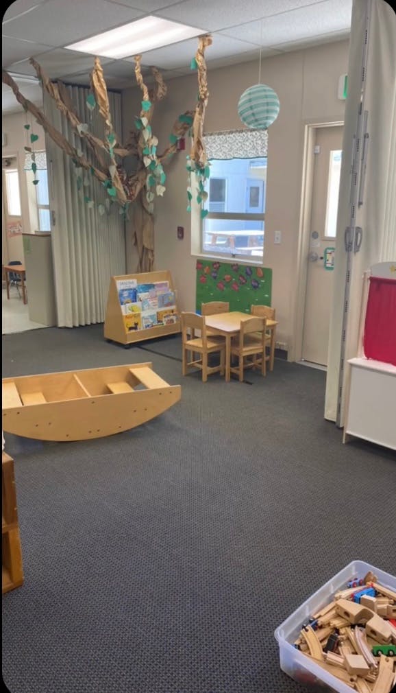 Classroom with small table and chairs, book display, and wooden rocker