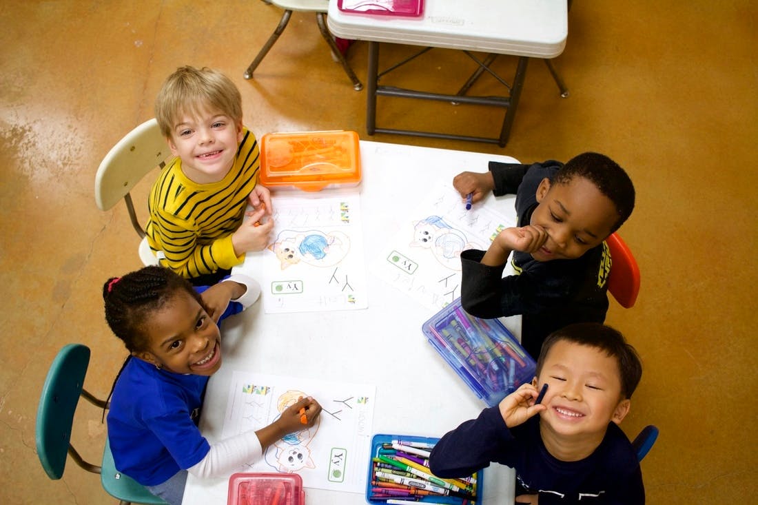 Four children drawing at a table