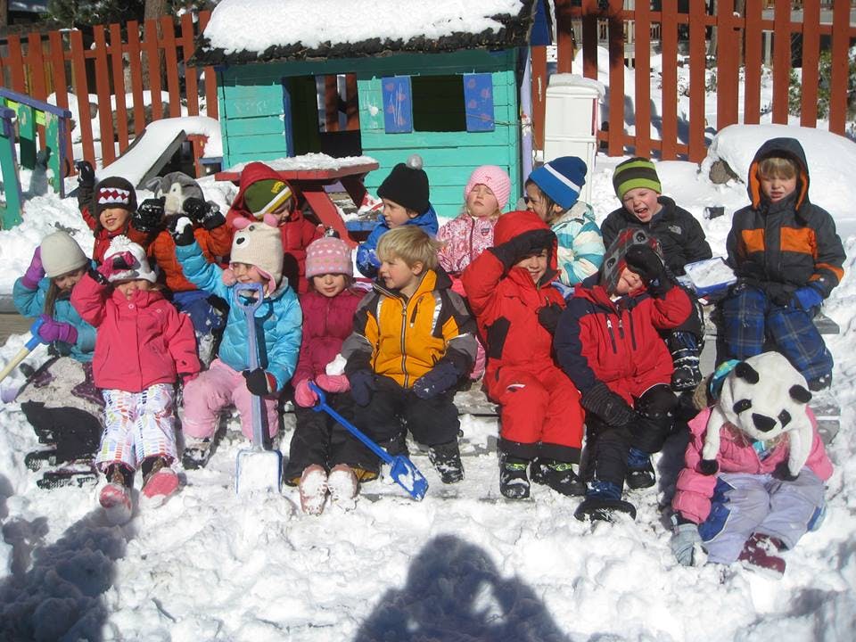 Group of children in winter clothing sitting in snow