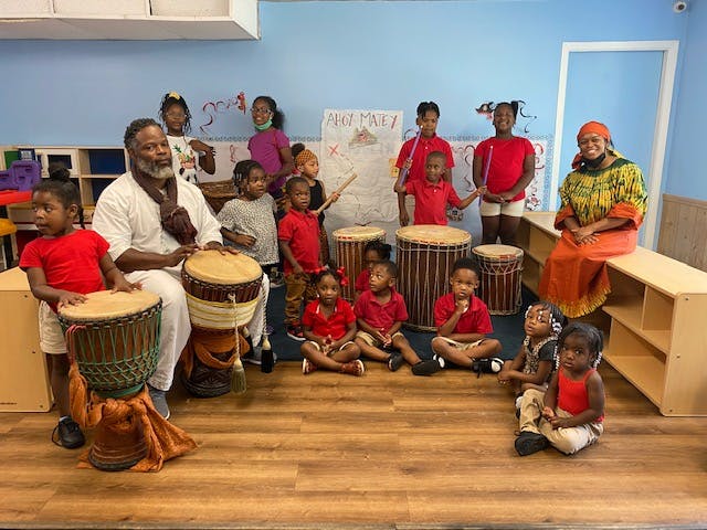 Adults and children playing drums in a classroom