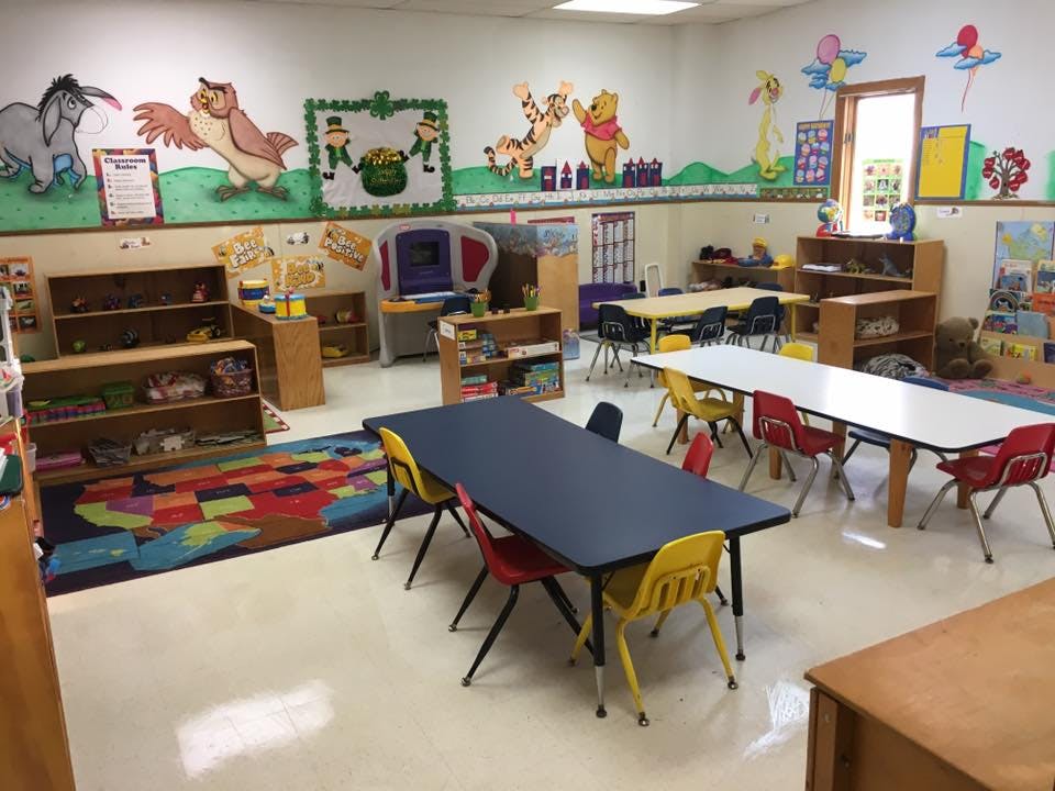 Classroom with small tables and chairs, shelves, and wall decorations