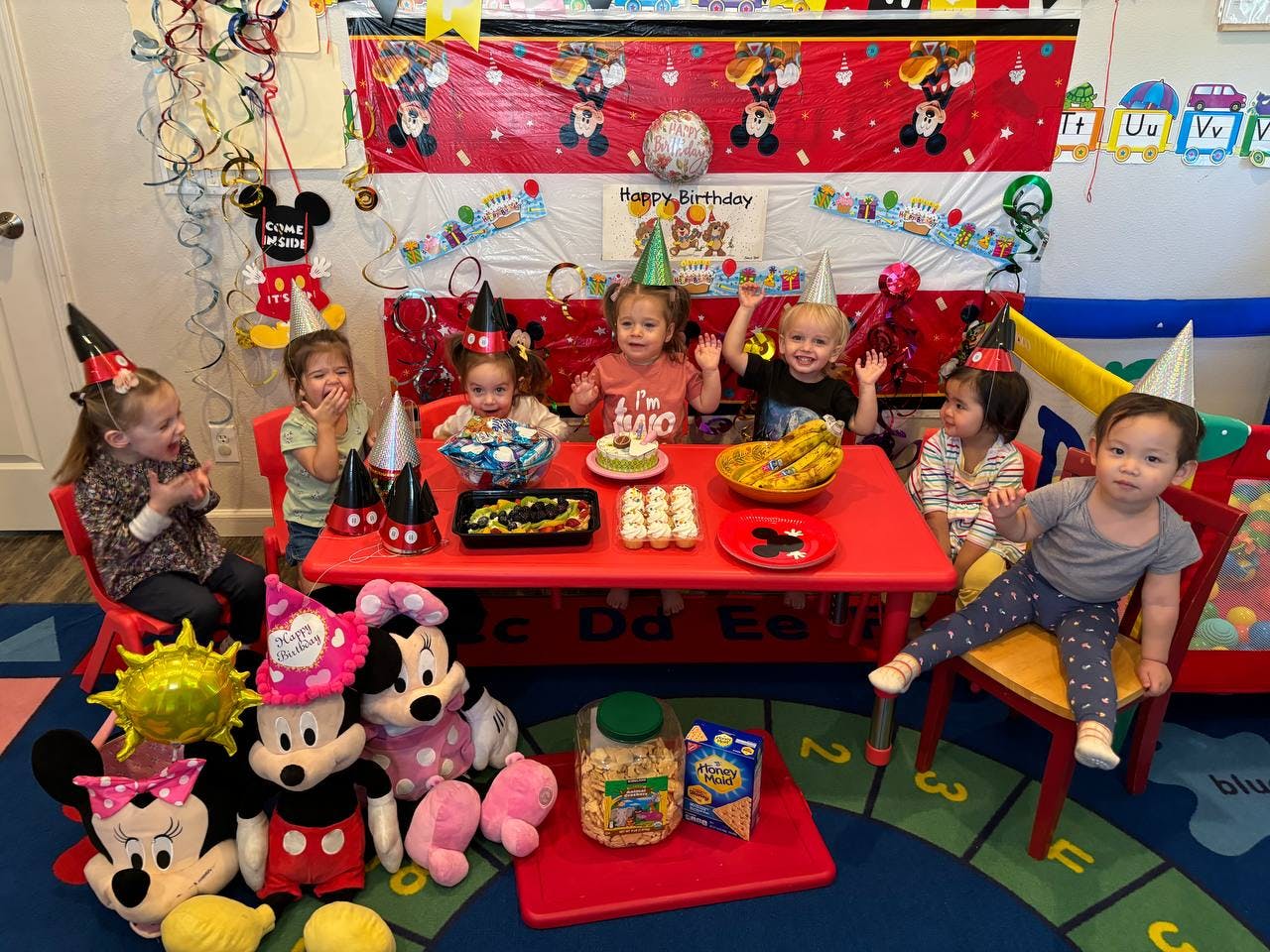 Children in party hats sitting around a table with food and decorations