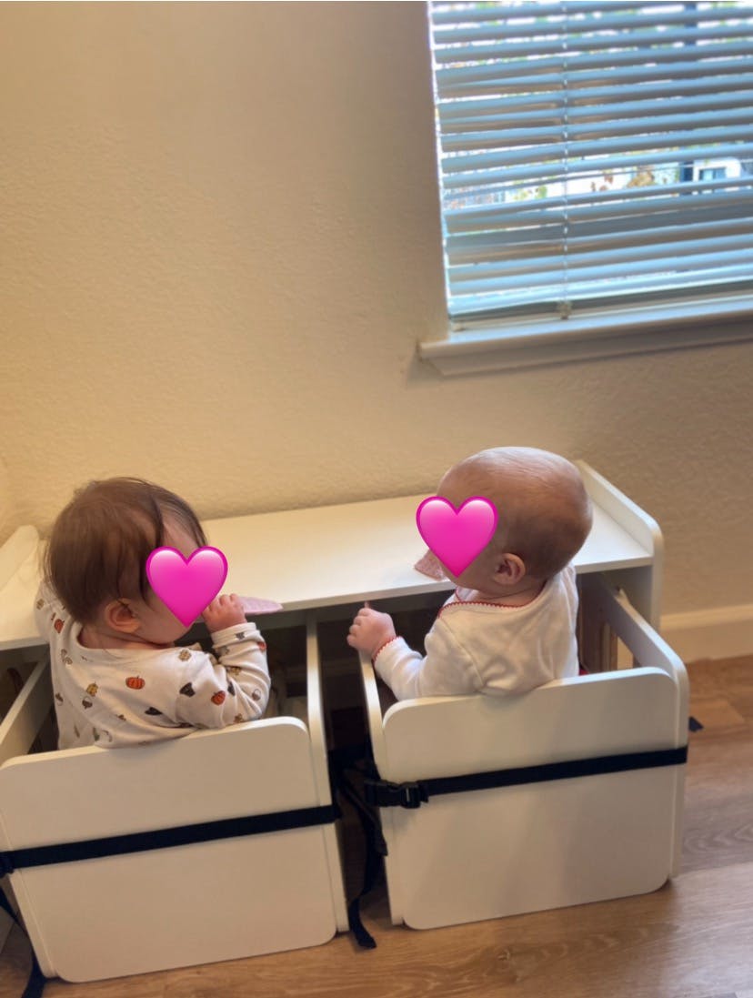 Two children sitting in high chairs at a table