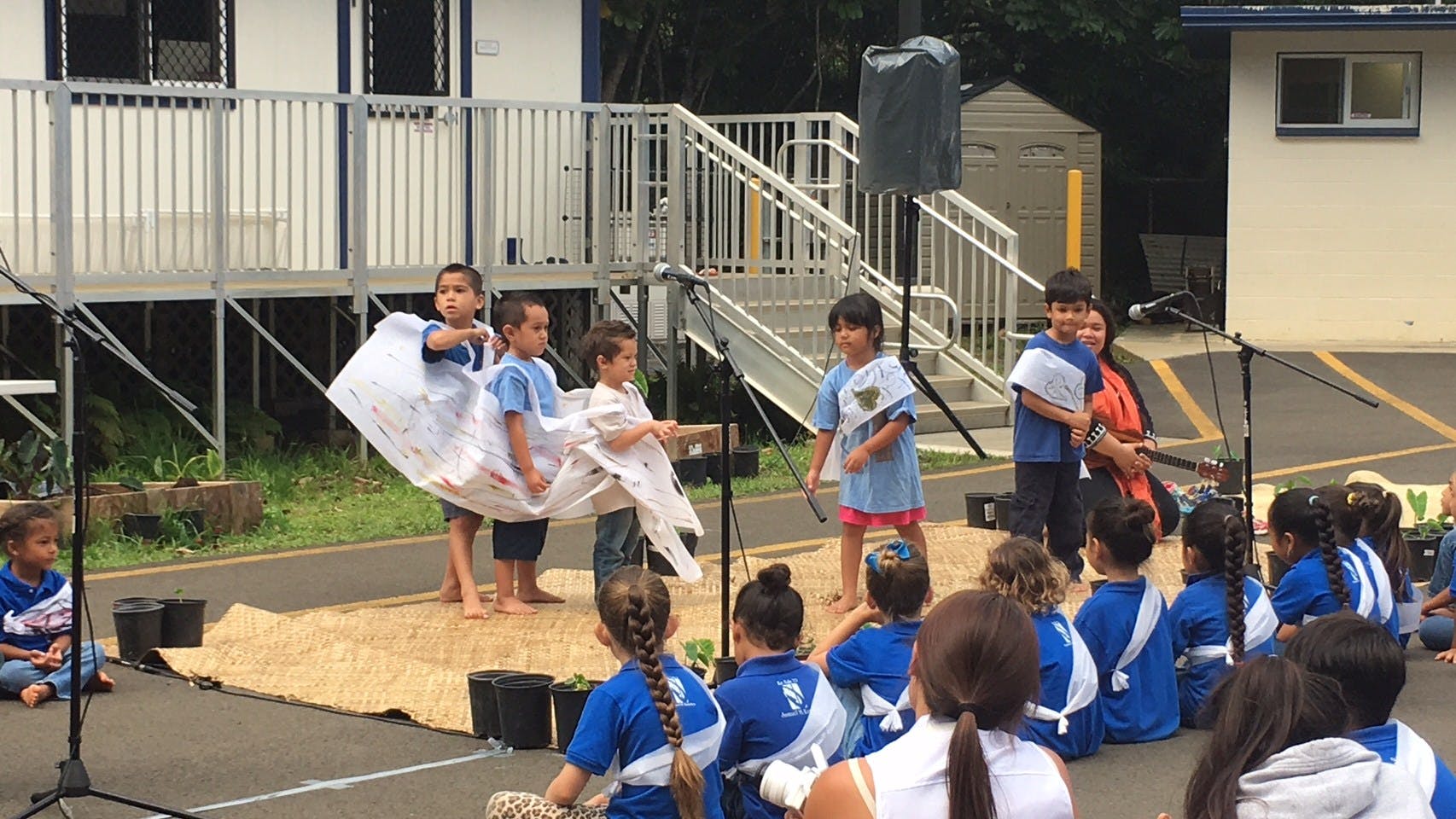 Children performing on a stage with an audience of children