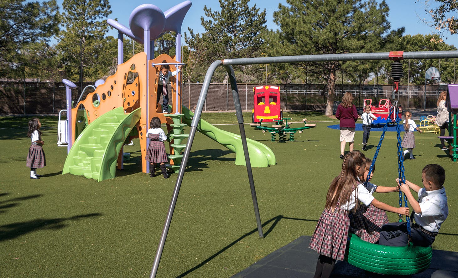 Children playing on a playground with swings and a slide structure