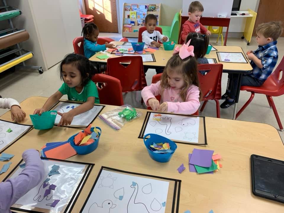 Children sitting at tables doing crafts in-class activities
