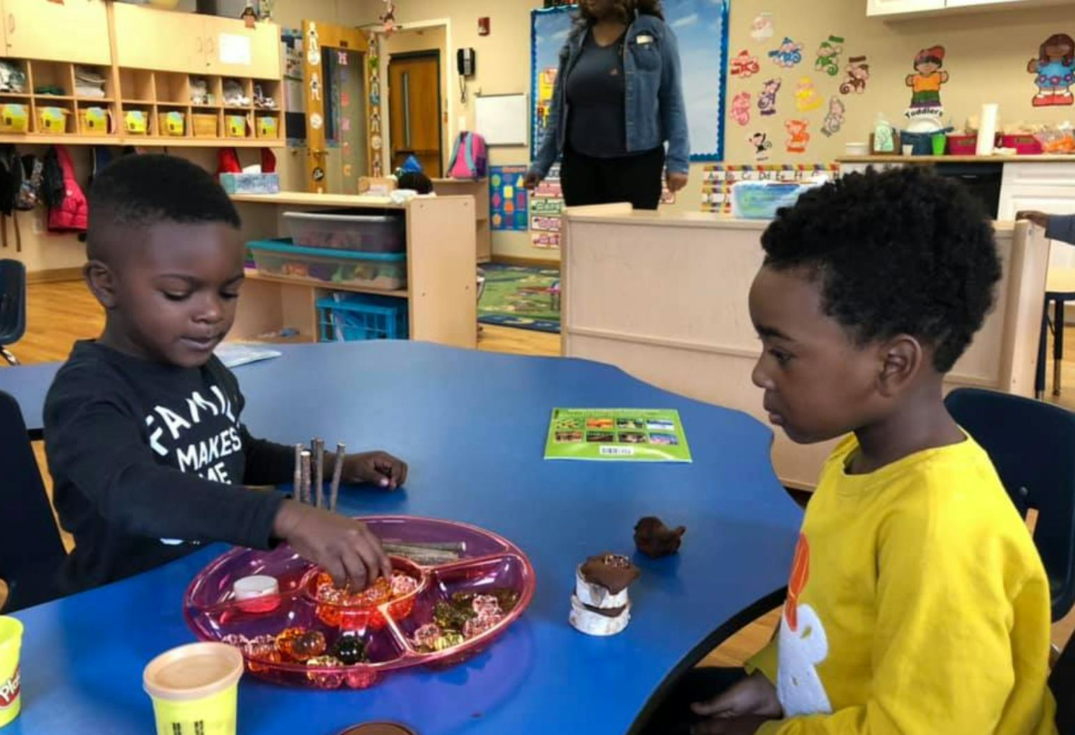 Two children at a table, one eating from a divided plate