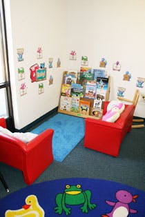 Children's reading nook with two red chairs and a bookshelf