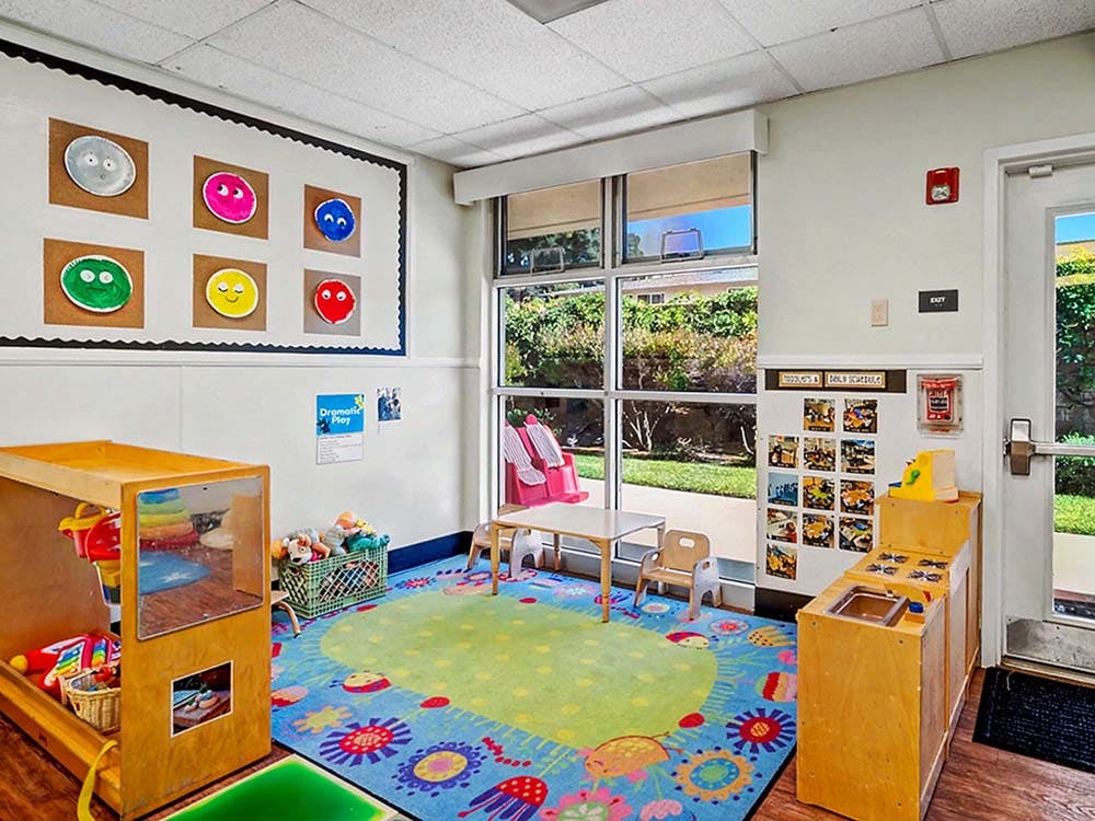 Colorful playroom with a patterned rug, small table and chairs, and toy kitchen