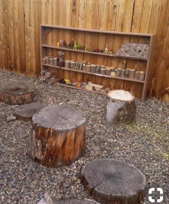 Outdoor shelving unit with toys and tree stumps on gravel
