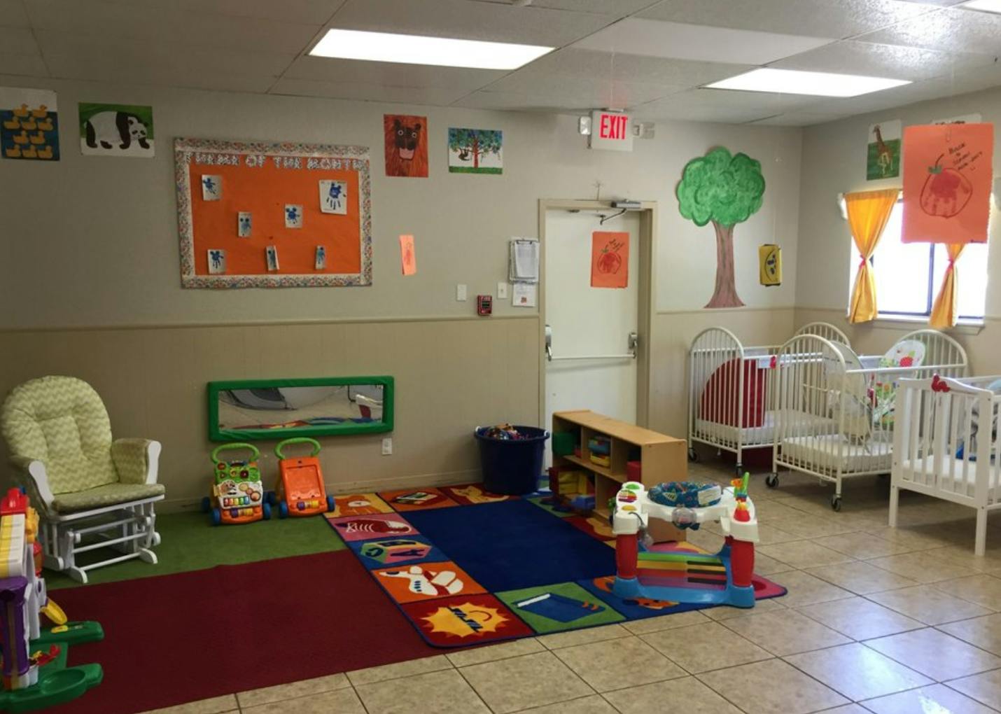 Nursery room with cribs, a rocking chair, and colorful play mats