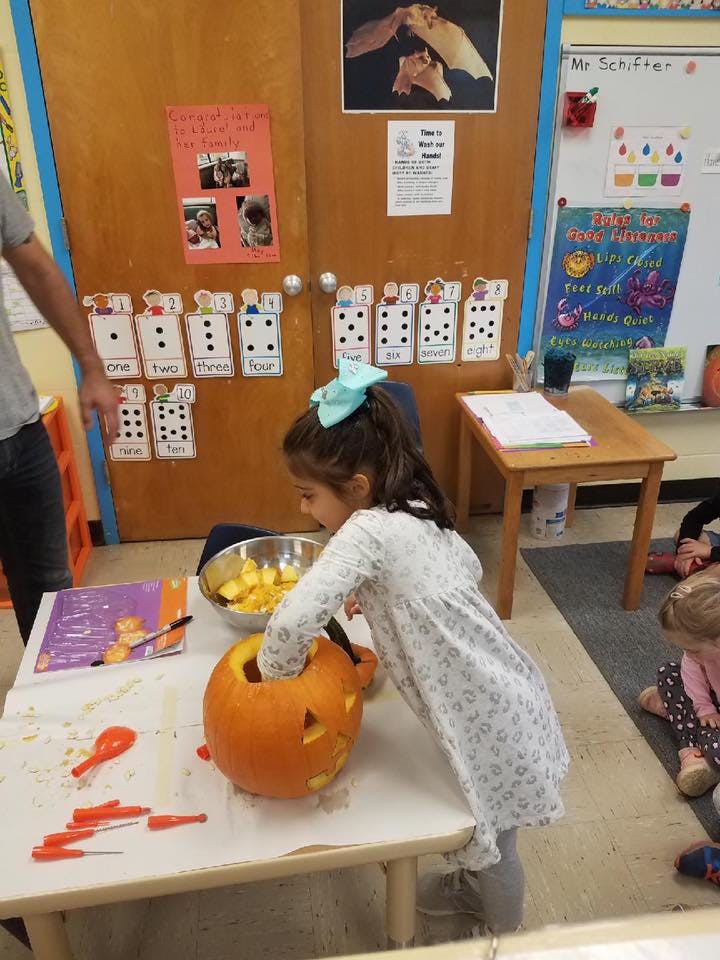 Child carving a pumpkin in a classroom