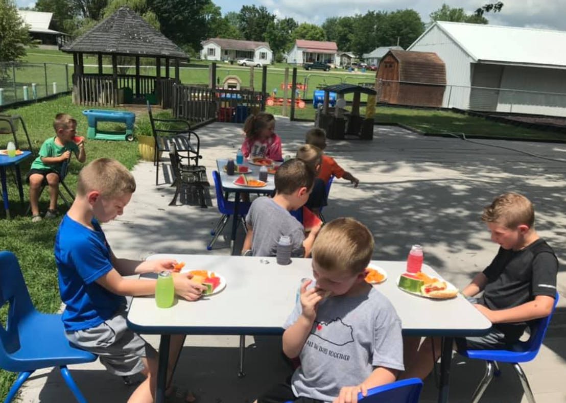 Children eating at tables outdoors