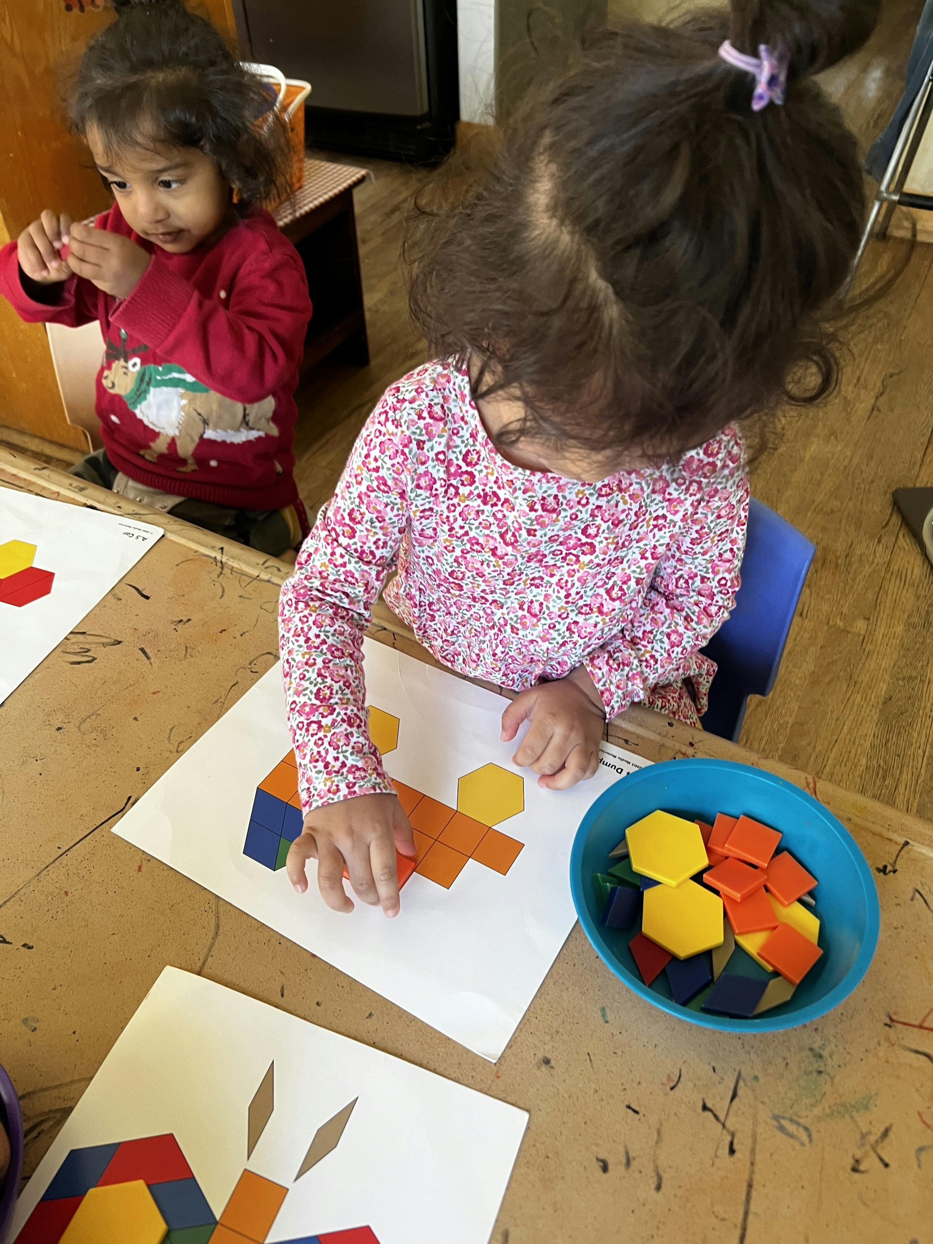 Children completing geometric puzzle patterns at a table
