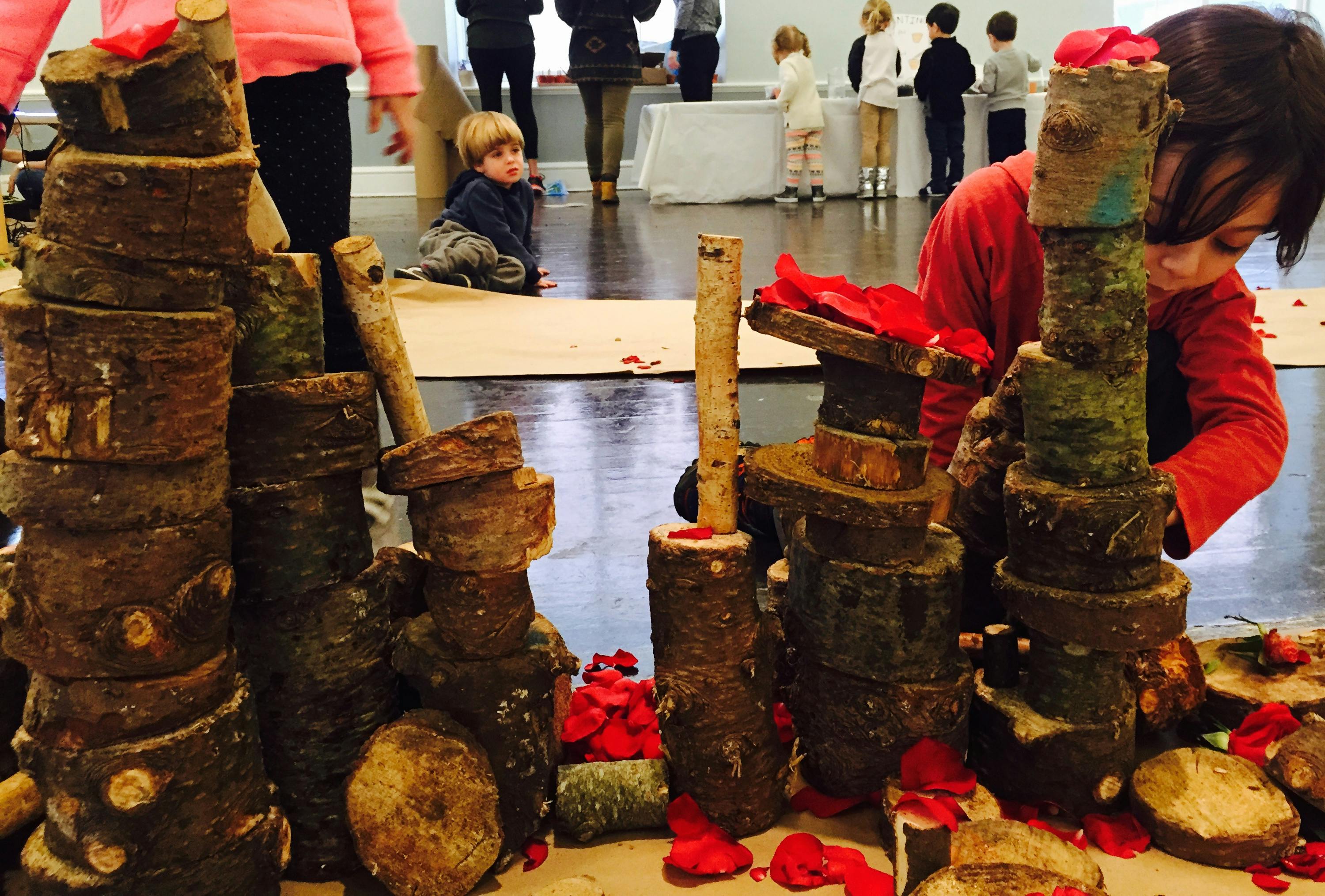 Child building with wood blocks and red fabric pieces