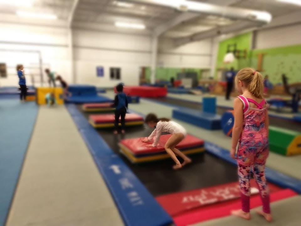 Children playing on gymnastics equipment in a gym